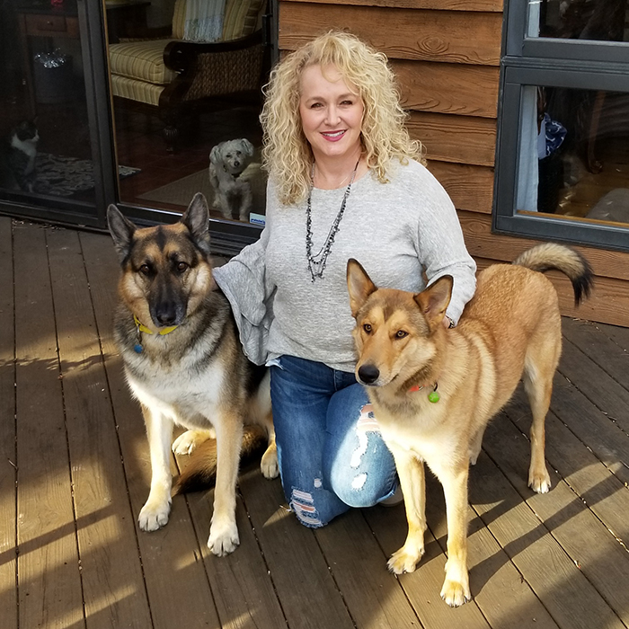 Nicole Moore Johnson with her two dogs, and another dog and cat in the background
